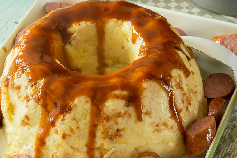 Een tulband van zuurkool met jus eroverheen en stukjes rookworst ernaast